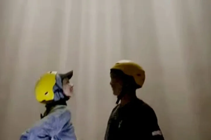 Two people wearing helmets facing each other in a misty environment.